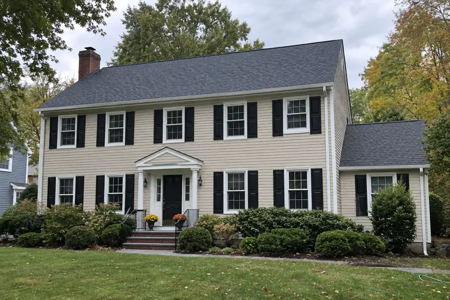 Colonial house with a newly installed charcoal shingle roof and white gutters.