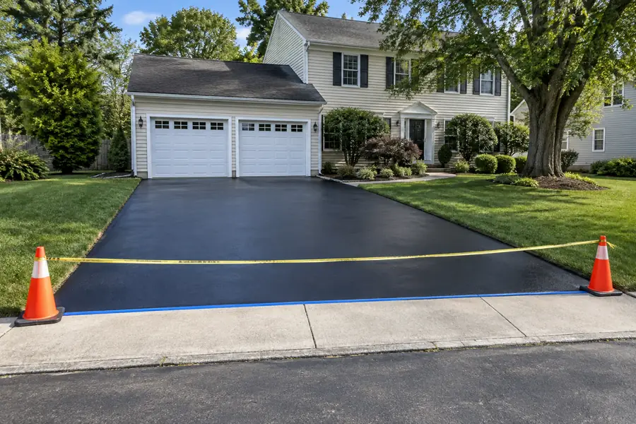 Freshly sealcoated asphalt driveway taped off while the sealer cures.