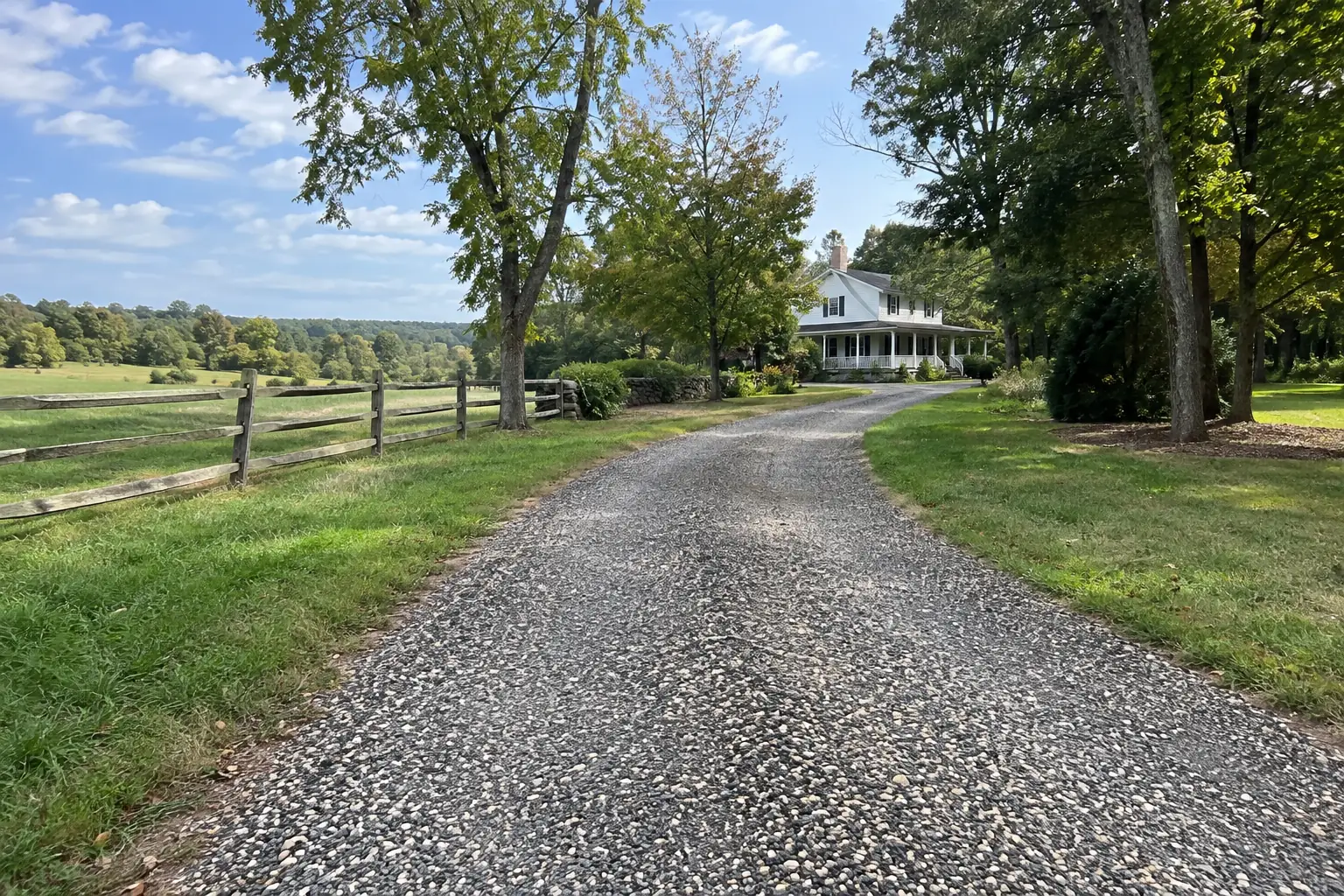 Tar and chip driveway with a textured crushed stone surface leading to a farmhouse.