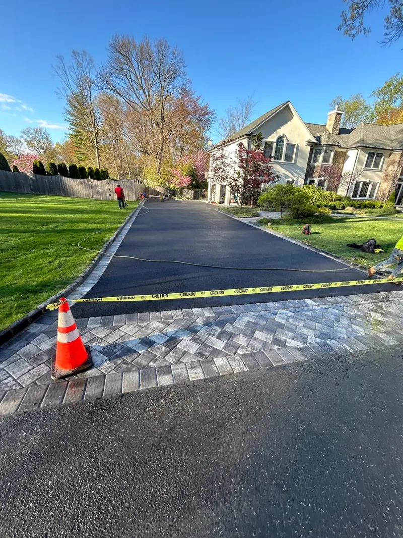 New asphalt driveway with a paver apron, taped off while it cures.