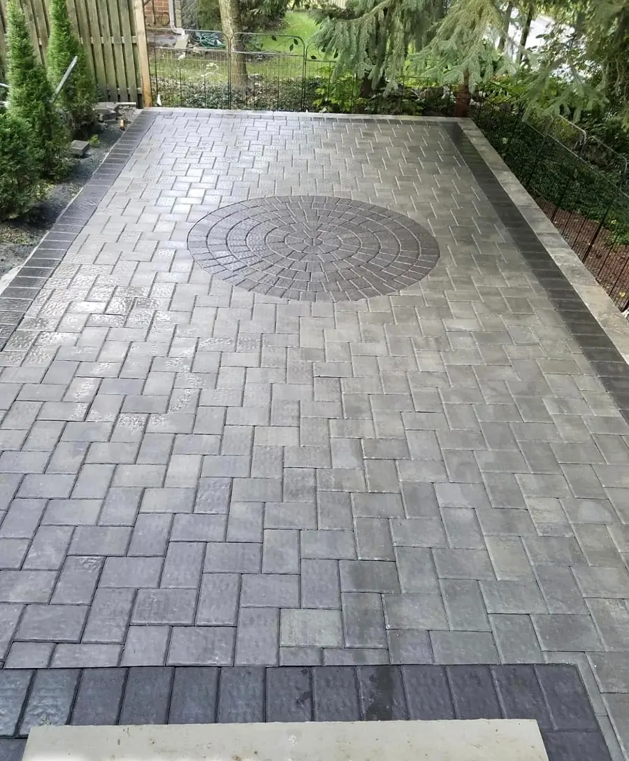 Paver driveway laid in a running bond with a circular medallion inlay and a contrasting soldier course border.