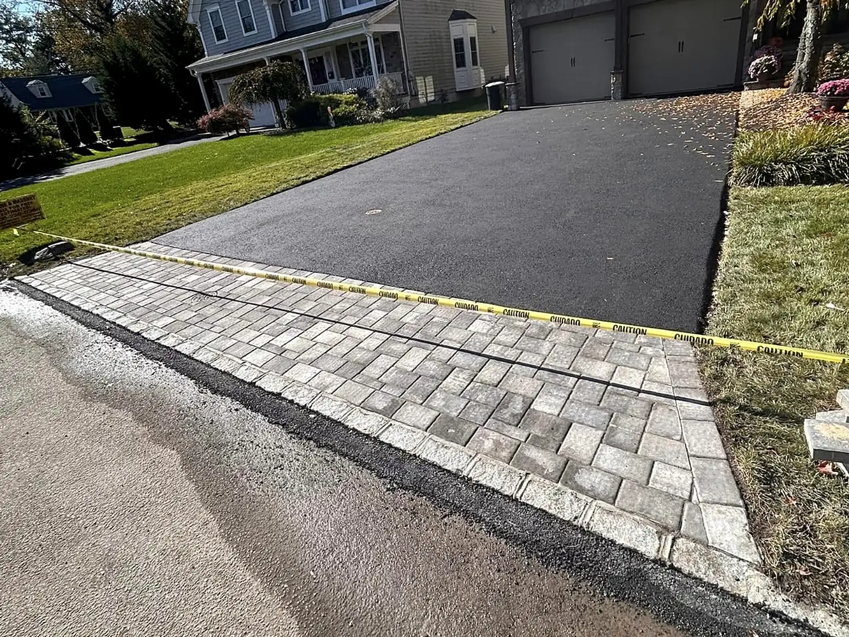 New asphalt driveway meeting a paver apron, a Courtyard Home Improvements job.