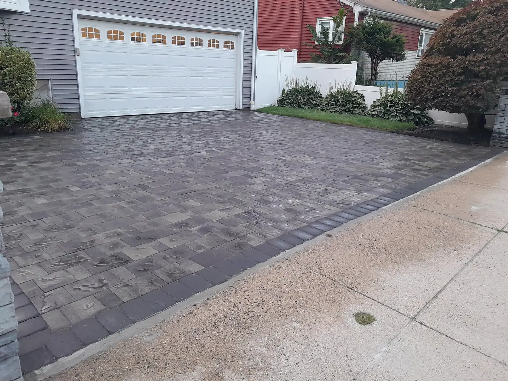 Paver driveway with a contrasting border in front of a two-car garage, a Courtyard Home Improvements job.