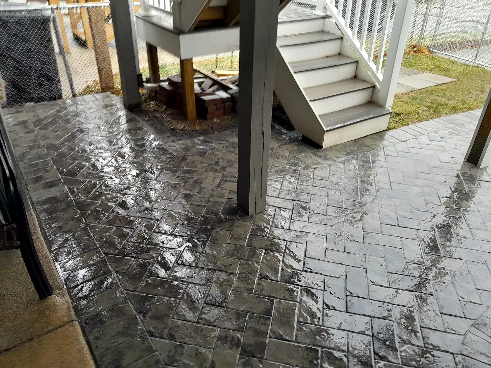 Stamped concrete patio with a slate texture finish set under a raised deck.