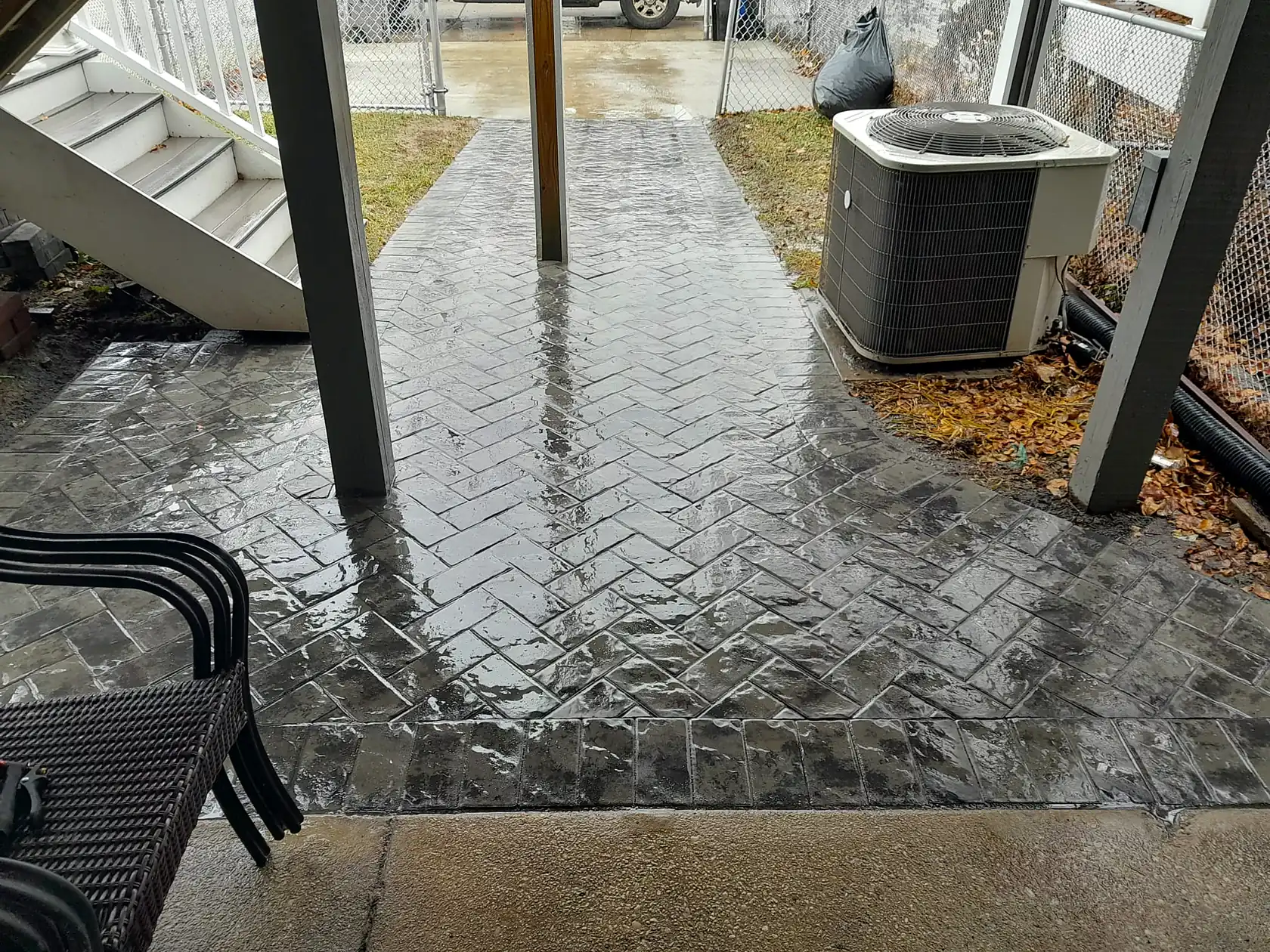 Stamped concrete patio under a raised deck, freshly sealed.